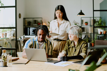Diverse group of gen Z man and women wearing casual clothes working together on business project in...