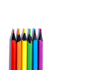 Set of colored pencils in the colors of the LGBT flag on a white background with copy space