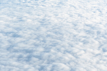 Wide carpet of soft white cumulus clouds high in the sky. Aerial view, abstract nature background