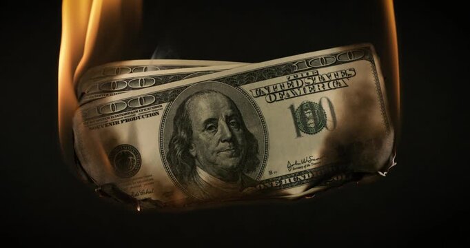 USA dollar bill money is burning in the fire, the concept of the economic crisis of inflation and currency devaluation.