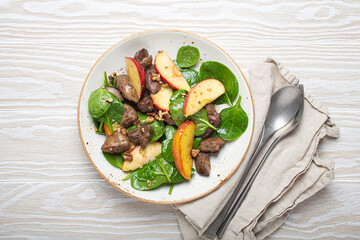 Healthy Salad with Iron Rich Ingredients Chicken Liver, Apples, Fresh Spinach and Walnuts on White Ceramic Plate, White Wooden Background From Above.