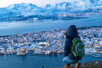 Obraz premium a blonde female woman traveler on top of the mountain in tromso norway in winter