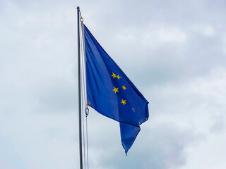 A vibrant European Union flag proudly waving beneath an expansive, cloudy sky, representing unity among nations