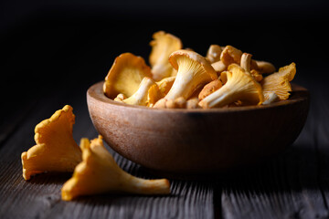 Chanterelle mushrooms in a wooden bowl on rustic wooden table close up. Food photography