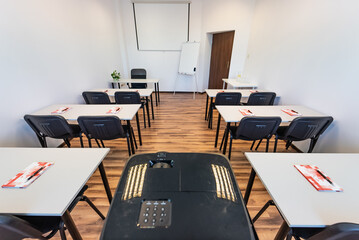 Conference room with benches, tables and a projector. Empty Conference Room In Modern Office. Interior of a classroom with white walls and wooden floor.  Office Business.