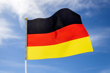 German flag in front of blue white sky 