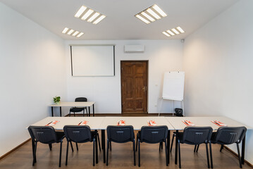 Conference room with benches, tables and a projector. Empty Conference Room In Modern Office. Interior of a classroom with white walls and wooden floor.  Office Business.