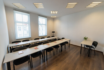 Conference room with benches, tables and a projector. Empty Conference Room In Modern Office. Interior of a classroom with white walls and wooden floor.  Office Business.