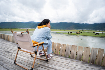 Travel woman sitting in chair looking at amazing mountains and lake view, wanderlust travel concept.