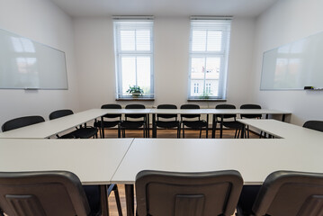 Conference room with benches, tables and a projector. Empty Conference Room In Modern Office. Interior of a classroom with white walls and wooden floor.  Office Business.
