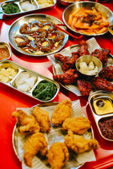 Traditional Korean food, Korean Fried chicken with spicy sauce with seaweed, Soy sauce pickled shrimp and Korean rice cake (Tteokbokki) with spicy sauce on red table. Traditional Korean street food.