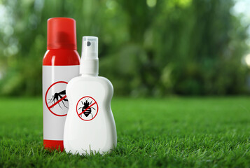 Different insect repellents in spray bottles on green grass outdoors, space for text © New Africa