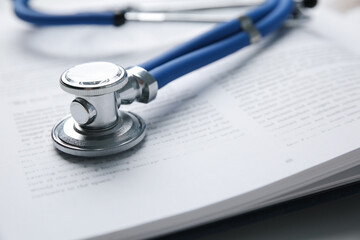 One medical stethoscope and book on table, closeup