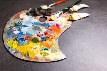 Fototapeta premium Artist's palette, brushes and paints on grey table, space for text