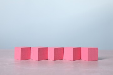 Blank pink cubes on light grey marble table