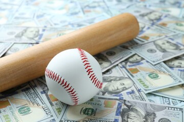 Baseball ball and bat on dollars bills, closeup