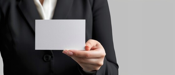 Naklejka premium Businessperson in a suit holding a blank card, perfect for corporate branding, networking, or advertising concepts on a neutral background.