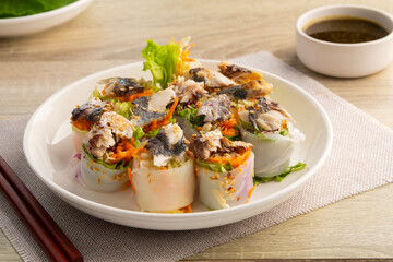 Thai mackerel with lettuce wrap and spicy seafood sauce,Vegetable Salad Rolls topped with fried mackerel fish in white plate.(Miang Pla Tu)