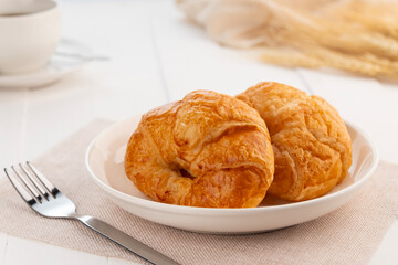 Croissant margarine in white plate with coffee cup on white wood background