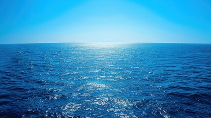 Fototapeta premium A serene and expansive view of the blue sea stretching out to the horizon, where the azure waters meet the clear blue sky in a seamless union of color and light