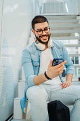 Young caucasian man student listening to music on stairs near university
