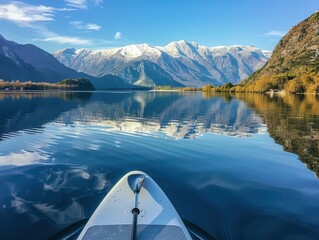 paddleboard resting in a serene lake surrounded by snow-capped mountains, reflecting the clear blue sky in a scenic, winter landscape