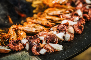 Cooking shrimp, octopus and sausage on a large grill