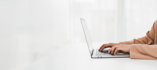 Hands typing on laptop in a bright, minimalist setting, emphasizing productivity and focus in...