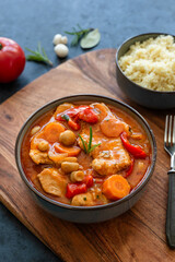 Fried pork loin in tomato sauce with mushrooms, red peppers and carrots served with couscous