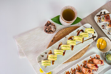 Ceramic tray with variety of salmon sushi roll with vegetables, avocado roll, grilled eel unagi in japanese restaurant
