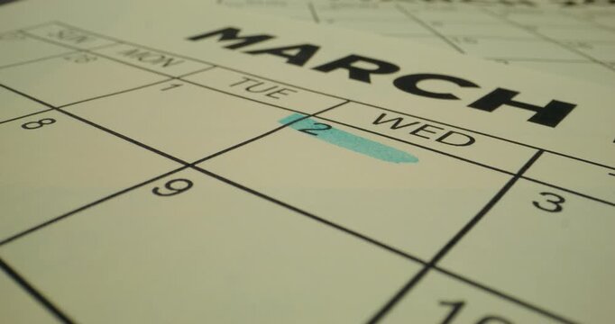 A person crosses out a number in the schedule table with a blue marker. Close-up of the marker, an unrecognizable person