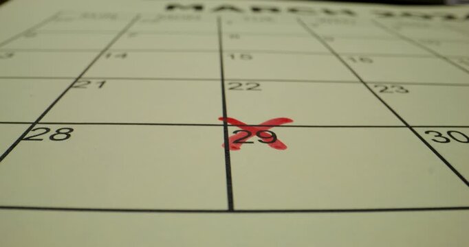 A person crosses out a number in the schedule table with a red marker. Close-up of the marker, an unrecognizable person