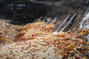 oriental dish of Uzbek cuisine is rice pilaf with vegetables and spices in cauldron in kitchen in...