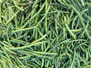 Green beans vegetable, top view background. Large amount of green beans in pods on market stall. Fresh green beans at farmers market in Greece. Healthy, vegetarian food.