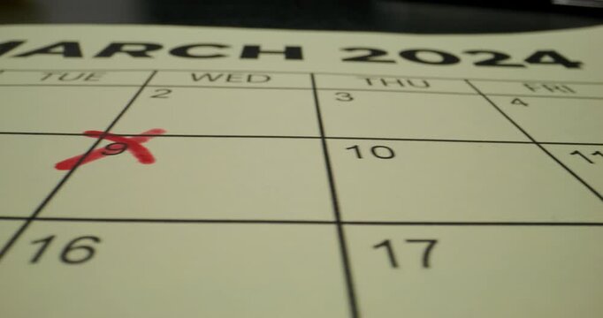 A schedule table with days of the week and numbers. One of the dates is crossed out with a red cross. Close-up