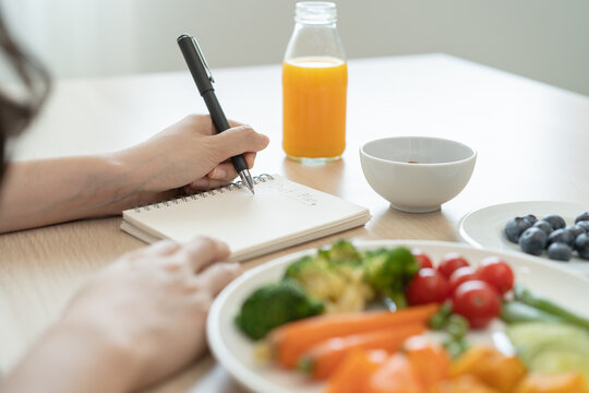 the person planning daily menu during dieting and writing diary to motivate.