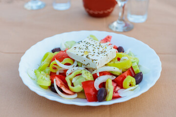 Greek salad with feta cheese on a white plate