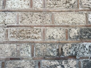 Brick wall texture, closeup of an old exterior surface as a background. Building face wall, convex joint line between dissimilar faded bricks brings character and dimensionality to vintage masonry.