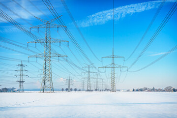 A lot of high voltage power line on the snowy field. Electrical energy transmission tower overhead...
