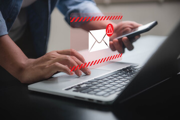 Person receiving spam email with warning alert on both laptop and smartphone. Cyber attack network, virus, spyware, cyber security and cybercrime.
