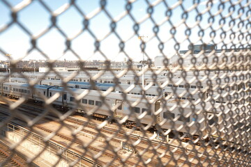 View of a train yard looking through a chain link fence during the day.  