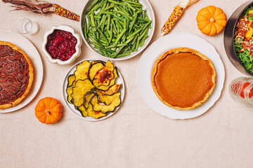 Thanksgiving table with homemade pumpkin pie, vibrant green beans, roasted squash, and a fresh salad.