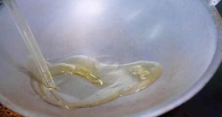 Close-up view of oil being poured into a hot wok with smoking ready for cooking, Close-Up View of Oil Flowing into a Pan in a Kitchen, Perfect for culinary, kitchen and cooking-related themes.