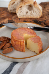 Rond des Vignes washed-rind cheese with.ivory-orange rind, strong nose with aromas, French soft cheese with orange rind