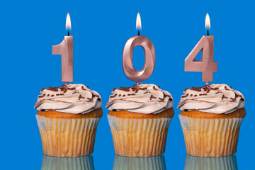 Birthday Cupcakes With Candles Lit Forming The Number 104.