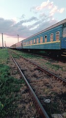 An old railway track with several blue passenger cars standing on the rails