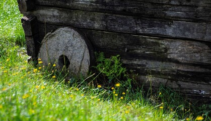 vintage mill wheel leaning on the wall of an old wooden barn in Austria