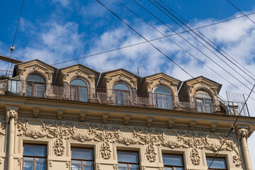 Side view of traditional roof of beige coloured facade with group of windows on wall of residential building in Saint Petersburg, Russia. Copy space. Architecture and city street background theme.