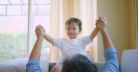 A happy Joyful child playing with father on a couch in living room. dad holding little kid bonding together lounge on sofa enjoy lifestyle activity spend leisure time with parent at home