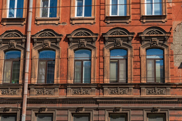 Side view of traditional ornate tawny coloured facade with group of windows on wall of residential building in Saint Petersburg, Russia. Copy space. Architecture and city street background theme.